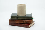 Tasse-poème en céramique beige, posée sur deux livres reliés