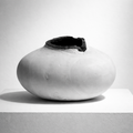 Vase céramique blanche à ouverture sombre sur le dessus, forme arrondie.