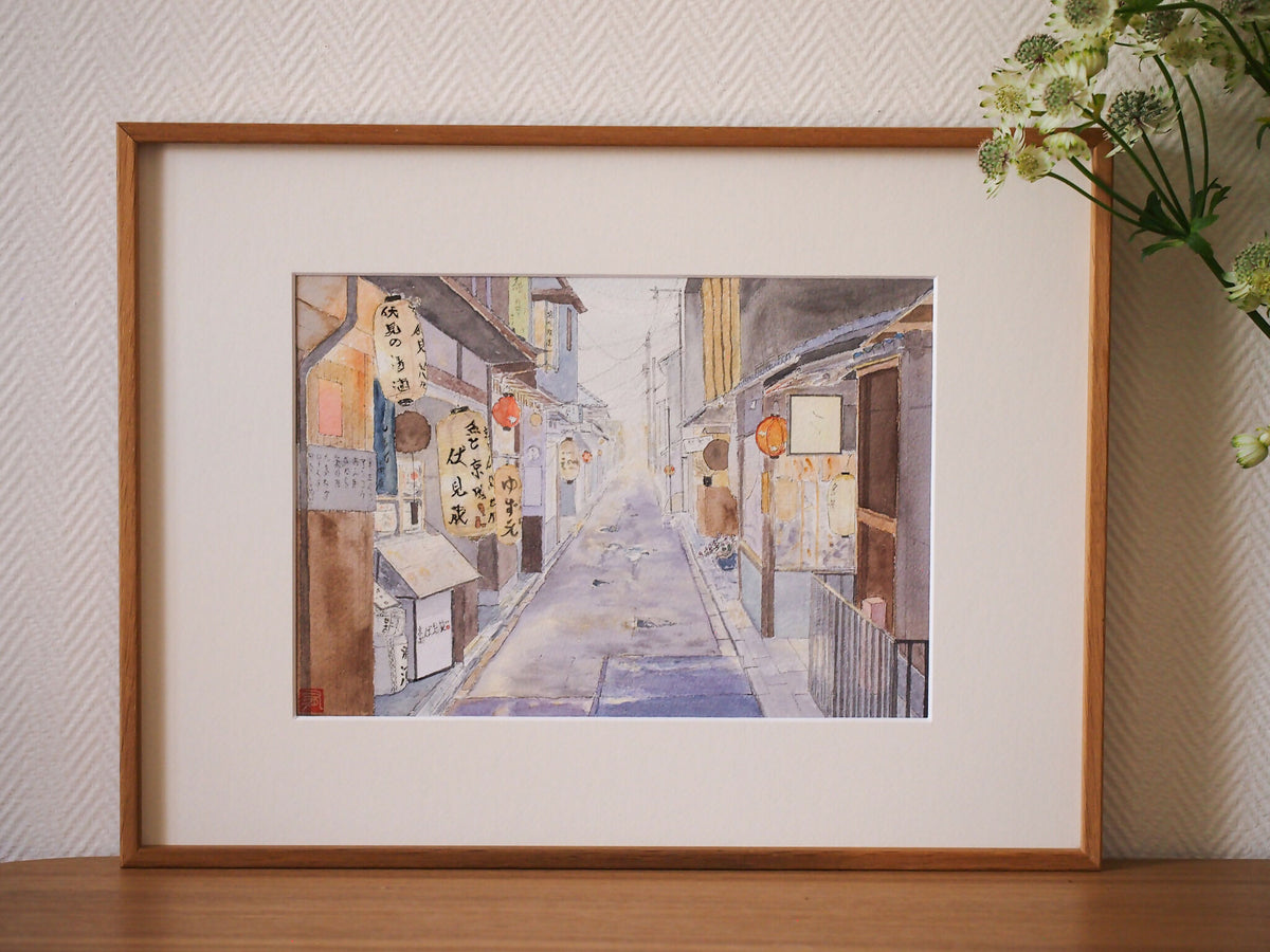 Impression d’art encadrée : ruelle pastel avec panneaux et lanternes orange.