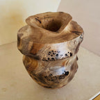 Vase en bois sculpté, ouverture circulaire et col évasé, motifs veineux et points noirs.