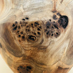 Détail du vase en bois sculpté : texture veinée et taches sombres, finition brillante.