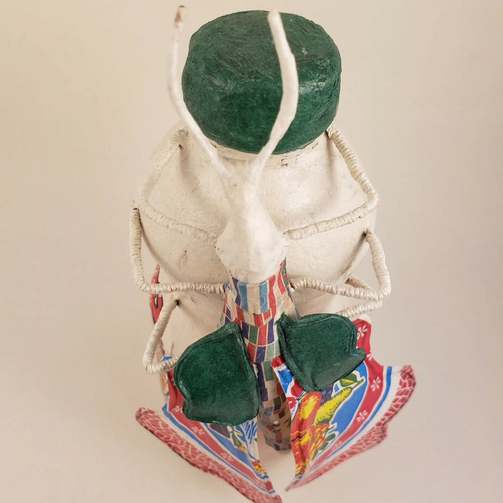 Sculpture posée sur une bouteille, vue rapprochée, capuchon vert, rubans et pièces vertes