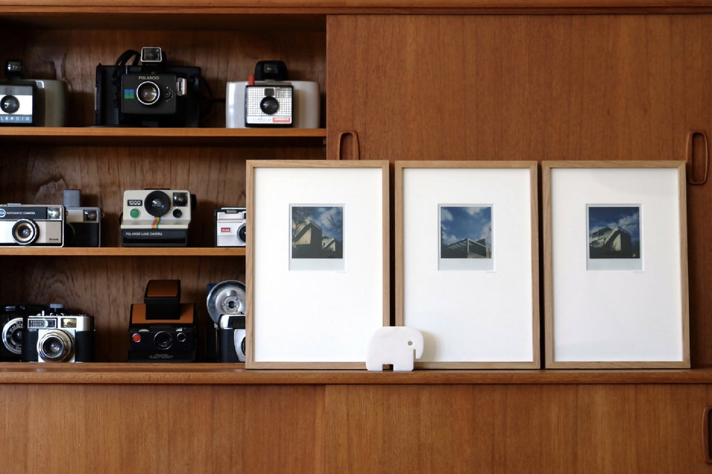 Triptyque de photos architecturales en trois cadres blancs, paysage bleu-gris