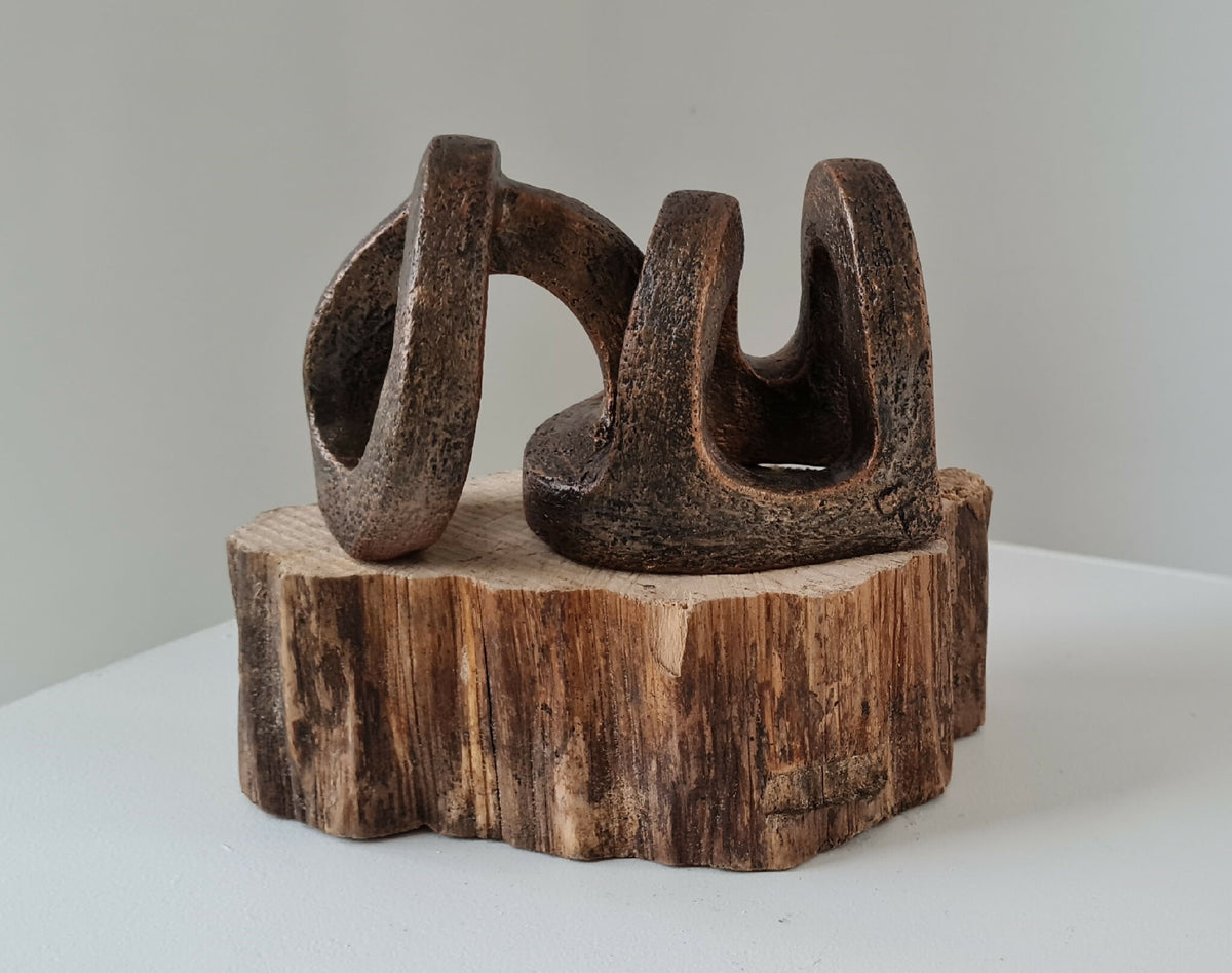 Sculpture abstraite brun foncé sur socle en bois massif, anneaux stylisés