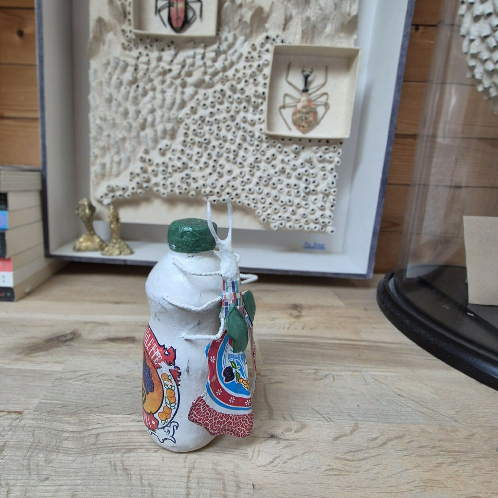Sculpture posée sur une bouteille, figurine en tissu sur surface en bois, capuchon vert