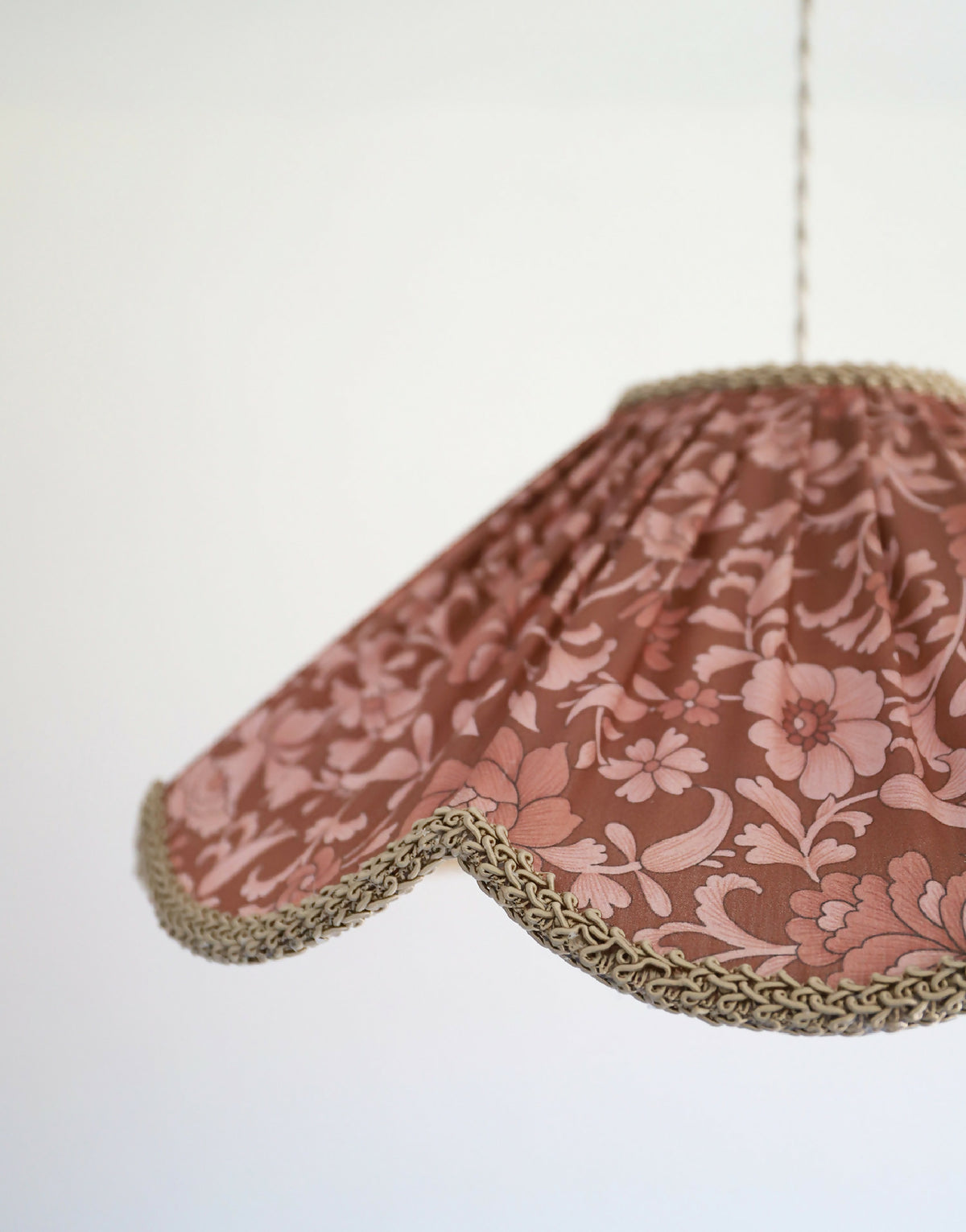 Suspension florale bordeaux imprimée, gros plan sur le tissu et la bordure dorée.