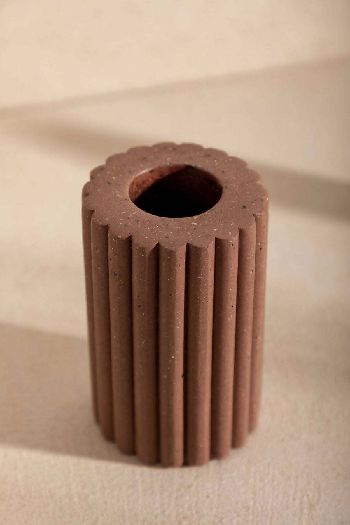 Vase en céramique brune striée, vue du dessus avec ouverture sombre.
