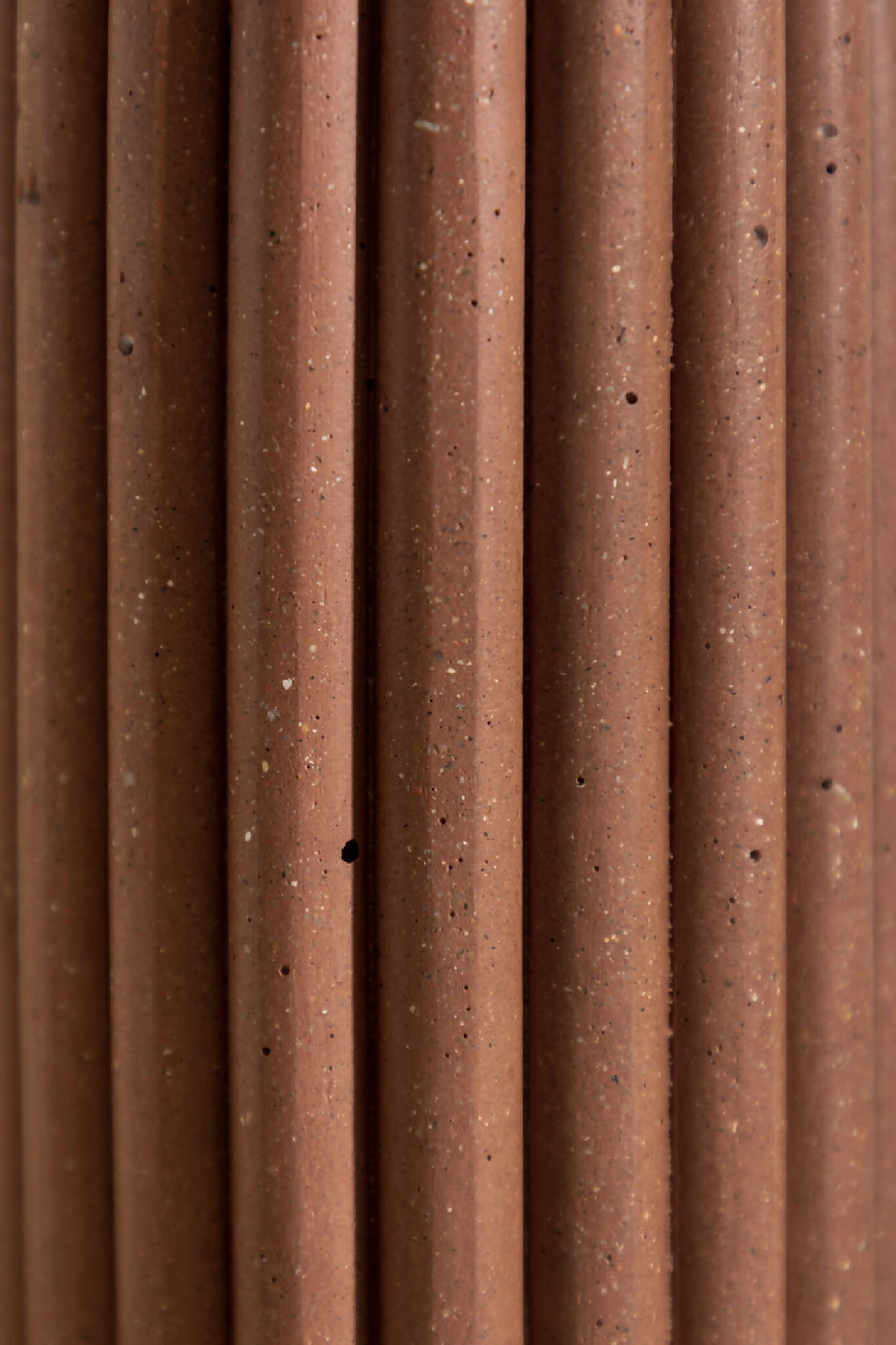 Vase en céramique brune, gros plan sur les stries verticales et les points.