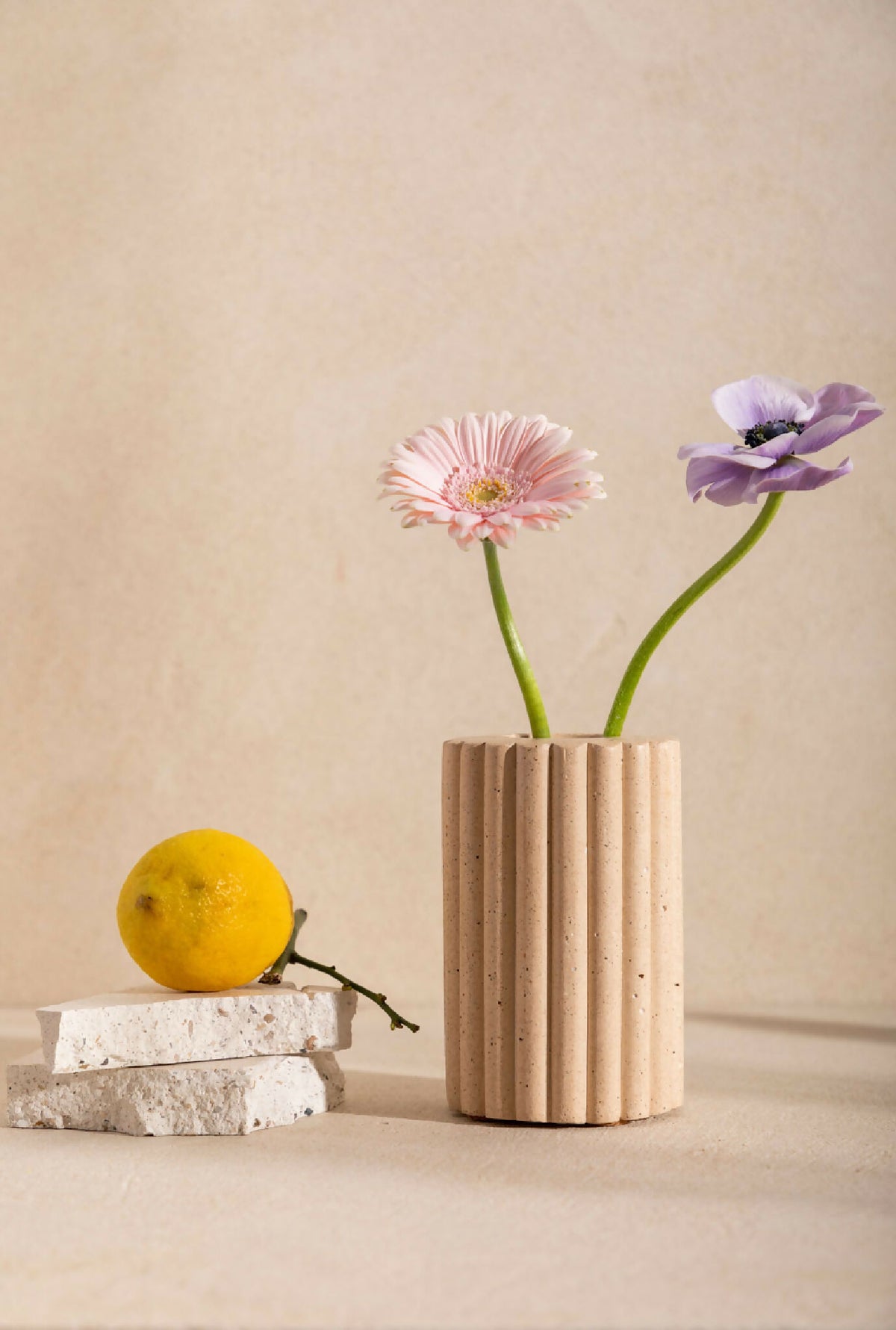 Vase en céramique beige striée, avec bouquet de fleurs roses et violettes.