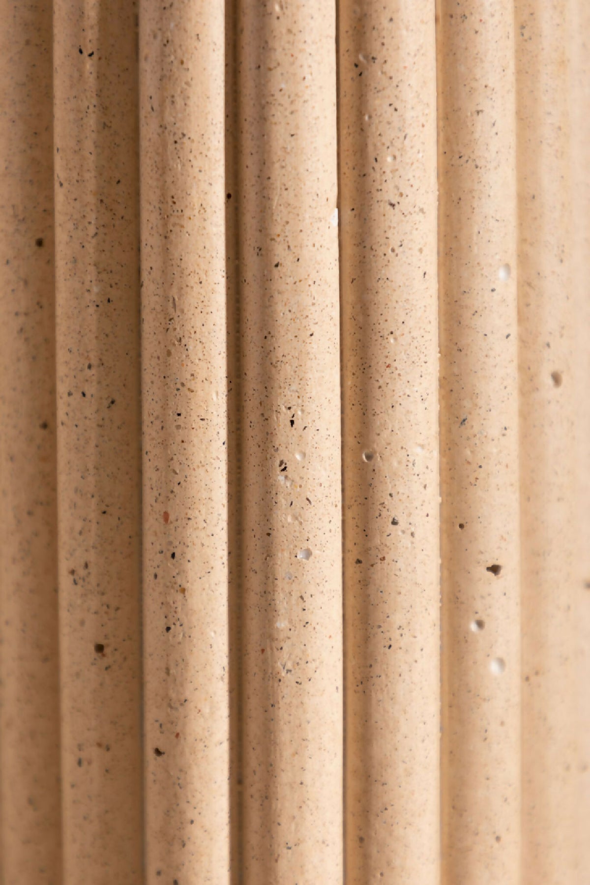 Vase en céramique beige texturée, stries verticales avec grains visibles.