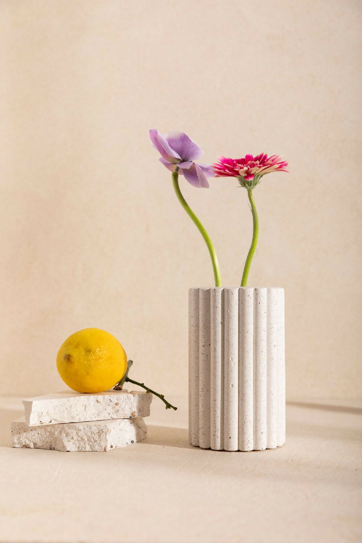 Vase GABRIEL en céramique blanche striée, avec ouverture et bouquet de fleurs.