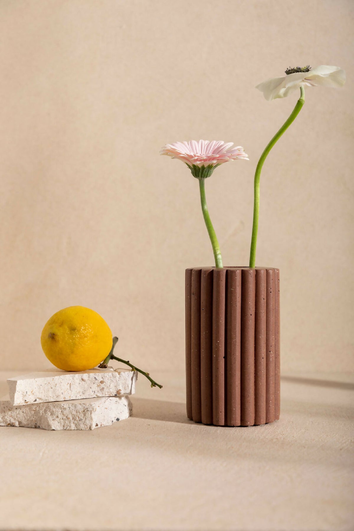 Vase en céramique brune striée, avec ouverture et fleurs rose et violettes.