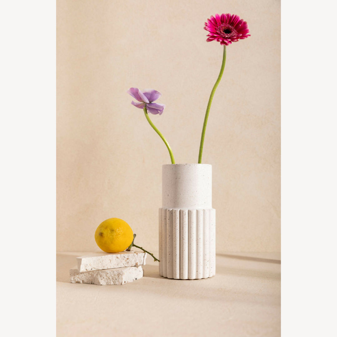 Vase DÉDÉ blanc strié avec fleurs rose vif et violette, tiges vertes.