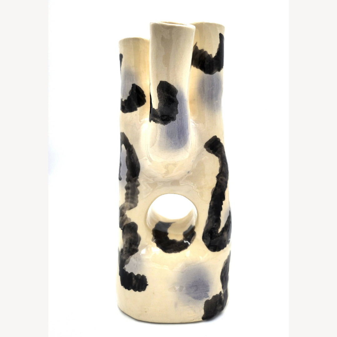 Vase en céramique crème avec motifs noirs abstraits et ouverture ovale au centre.