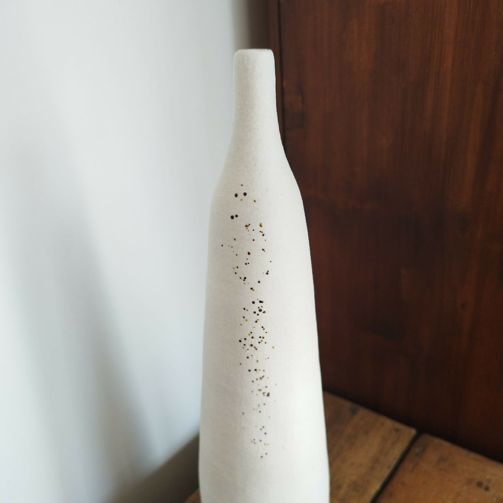 Vase en céramique blanc, col étroit, décor de points brun-noir et doré.
