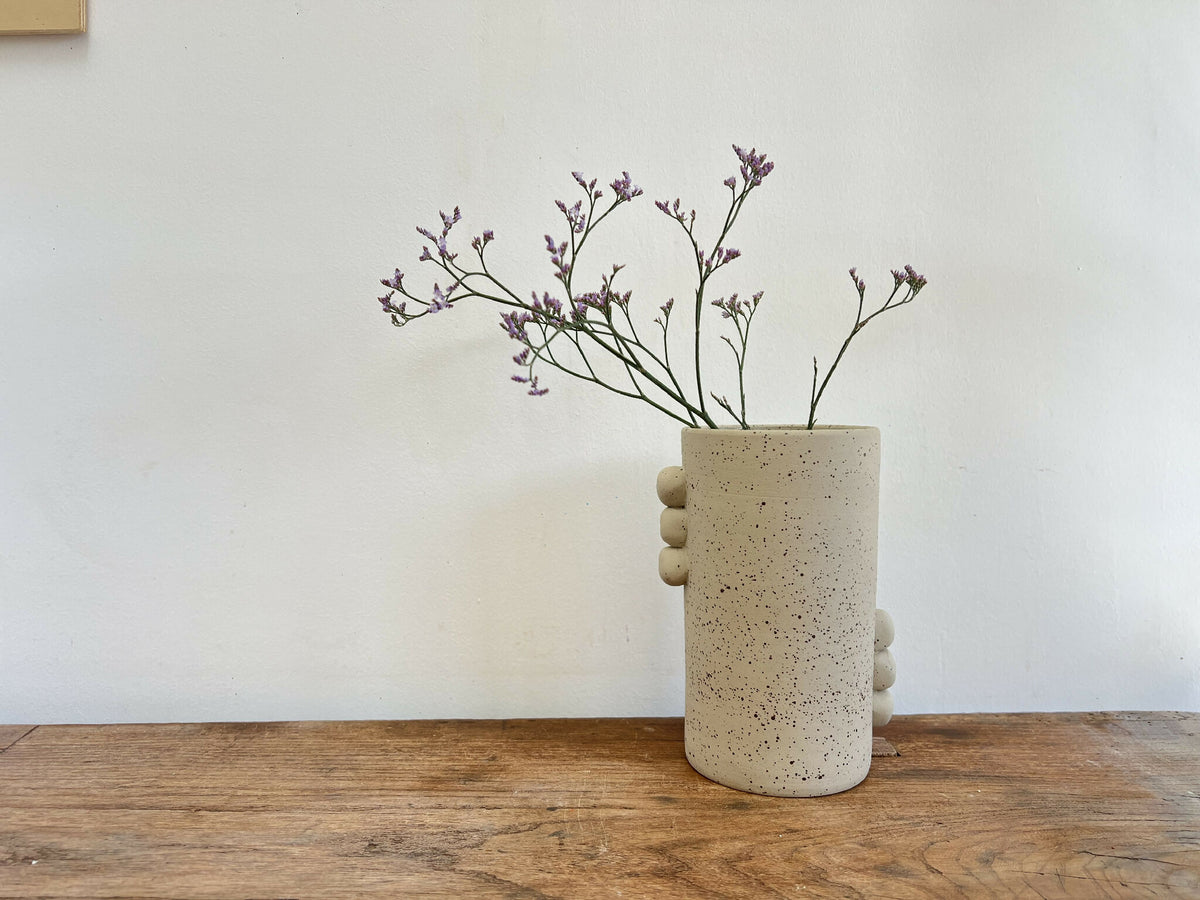 Vase cylindrique en grès beige piqueté, reliefs ronds sur le flanc.