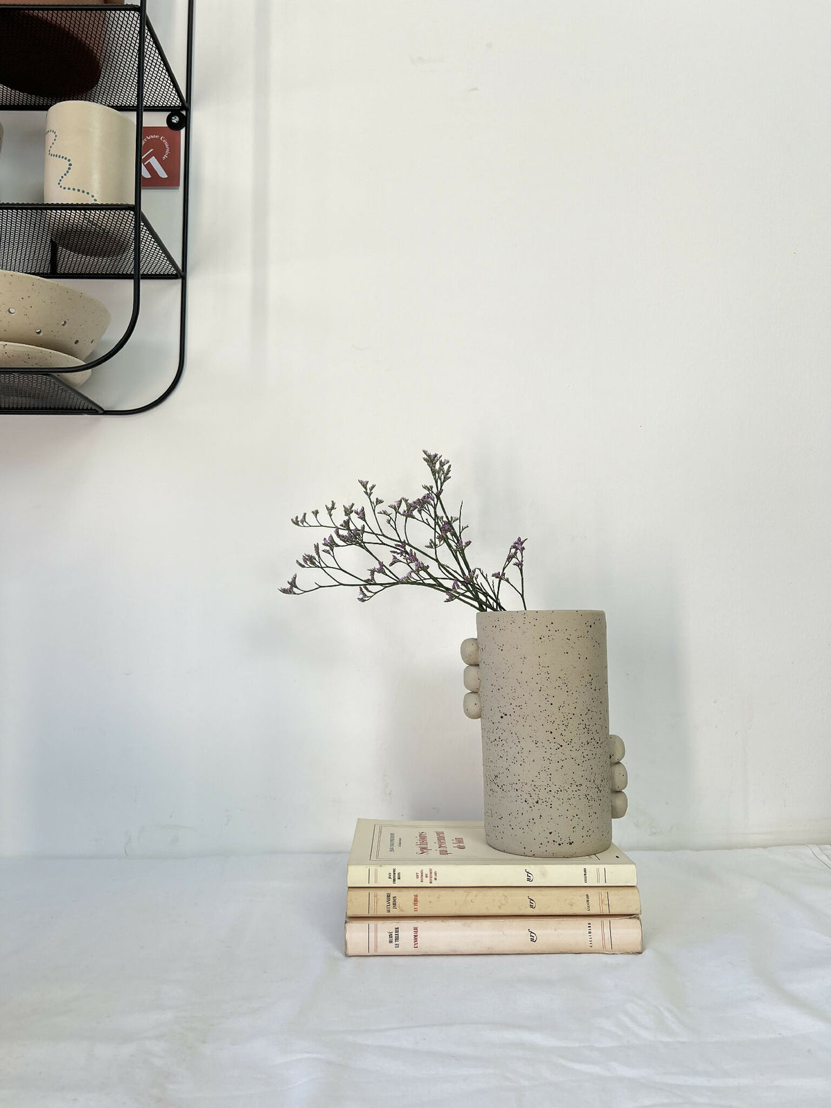 Vase cylindrique en grès beige piqueté avec fleurs séchées, reliefs ronds latéraux.