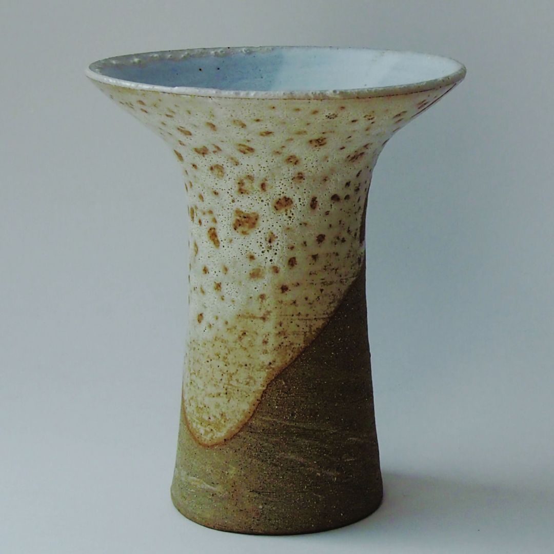 Vase tulipe en céramique beige et vert, surface tachetée, ouverture évasée.