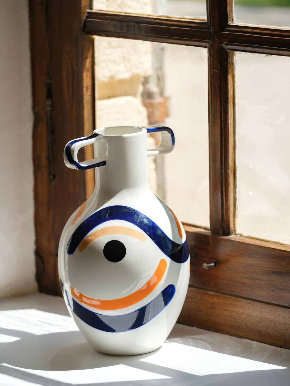 Vase buste en céramique blanche, anses et décor bleu/orange abstrait.