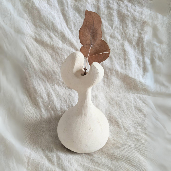 Vase en céramique blanche avec tige florale et feuilles brunes séchées