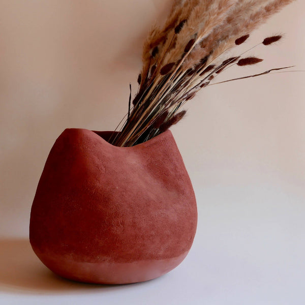 Vase en céramique rouge BRAZIL, forme arrondie, avec bouquet d’herbes séchées.