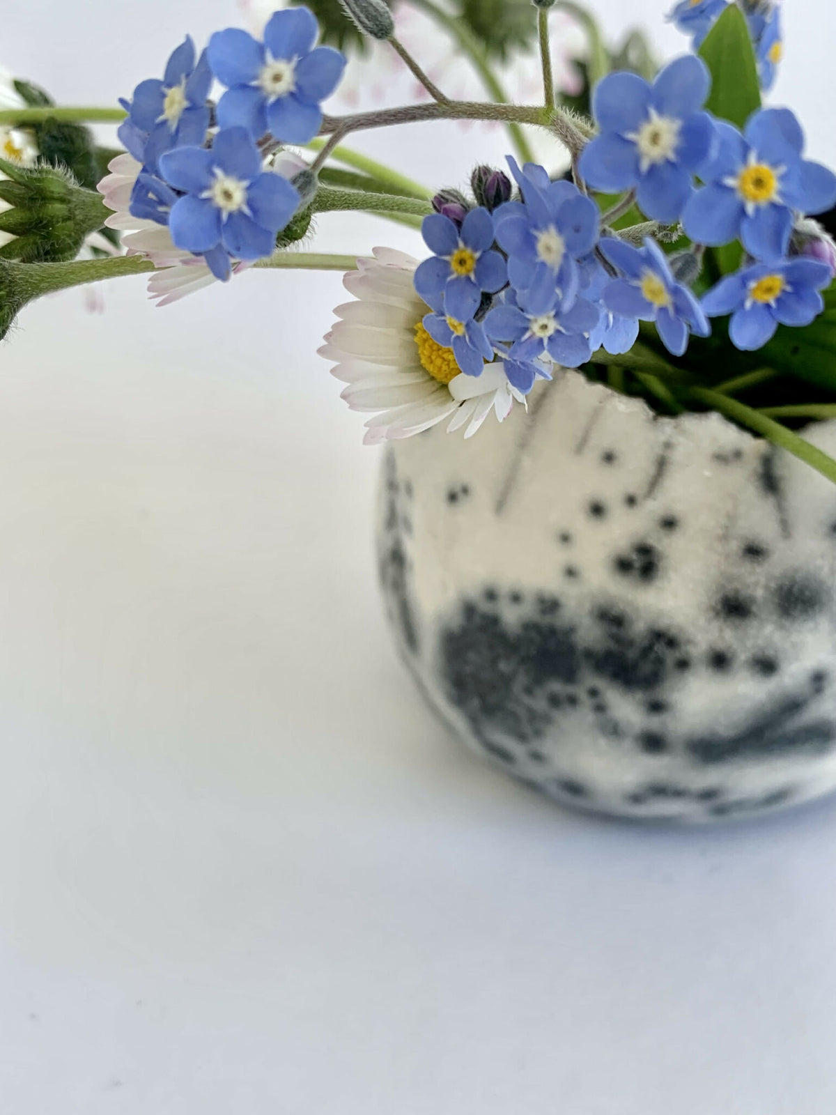 Vase boule en raku blanc à éclats noirs, bord noir, fleurs sur le dessus
