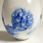 Vase goutte blanc avec grand motif bleu diffus, ambiance aquarelle.