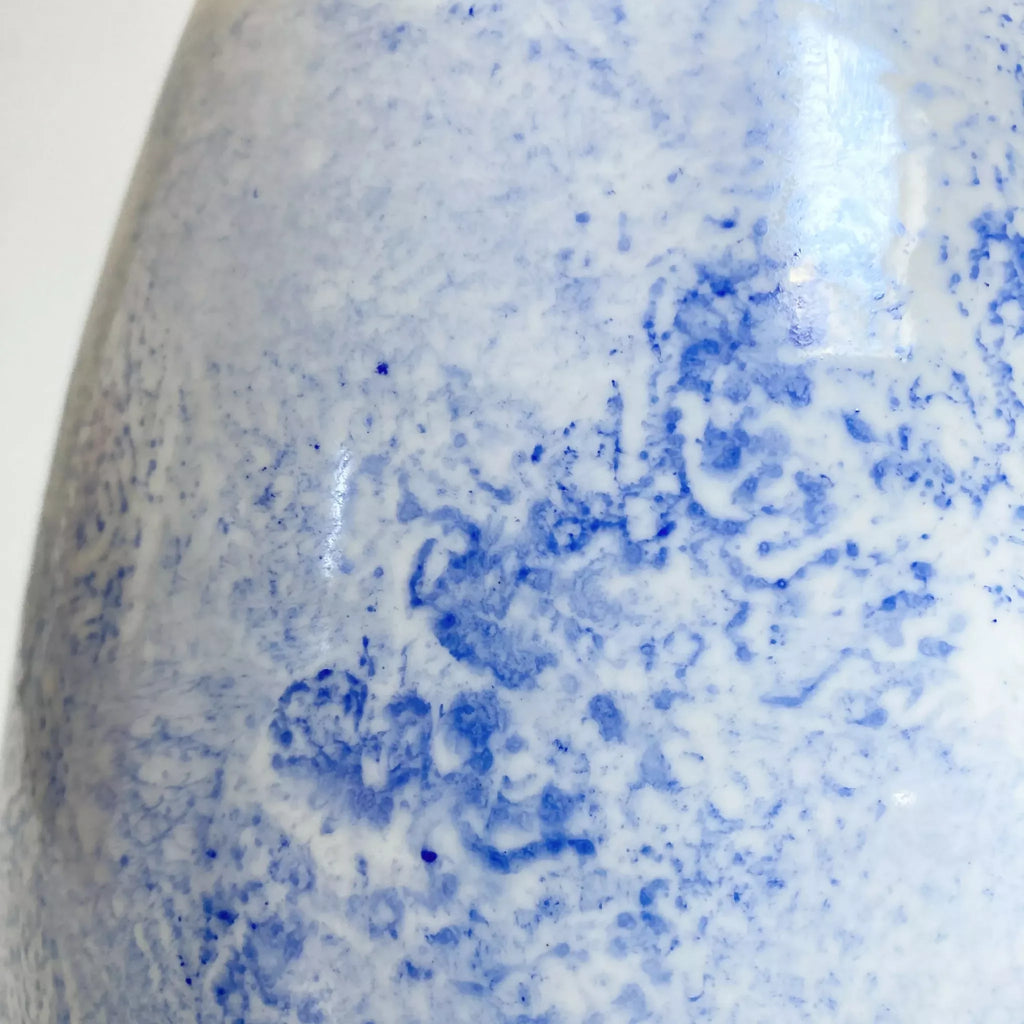 Vase goutte, gros plan décor bleu éclaboussé sur fond clair brillant.