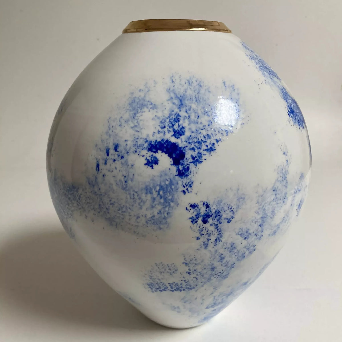 Vase en céramique blanc et bleu au décor nuageux, col doré