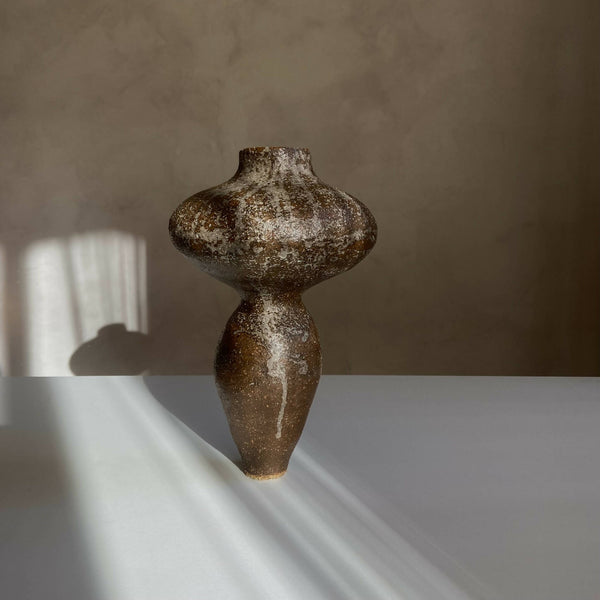 Vase sculptural brun foncé tacheté, silhouette arrondie et long goulot