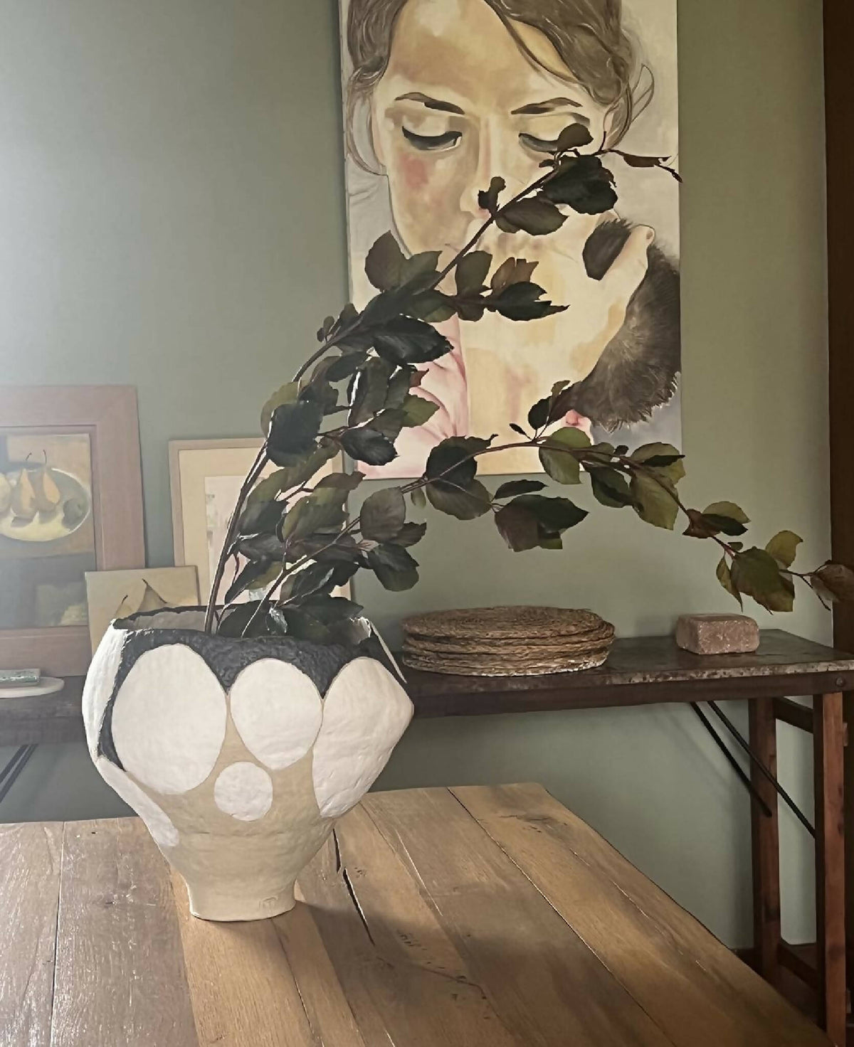 Grand vase beige à motifs galets blancs et bord noir, avec feuillage