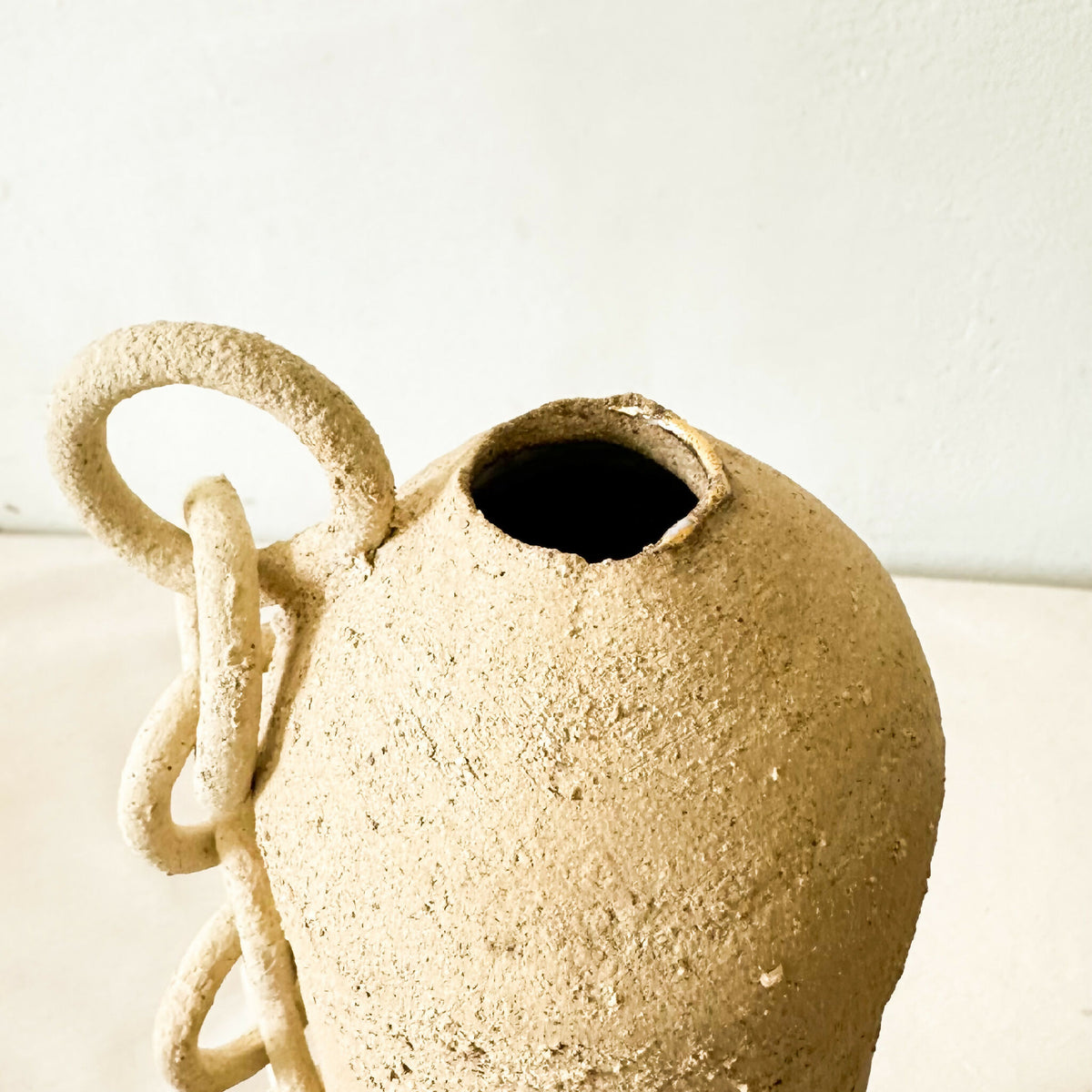 Vase en grès brut avec ouverture ovale noire et anneaux de chaîne sur le col