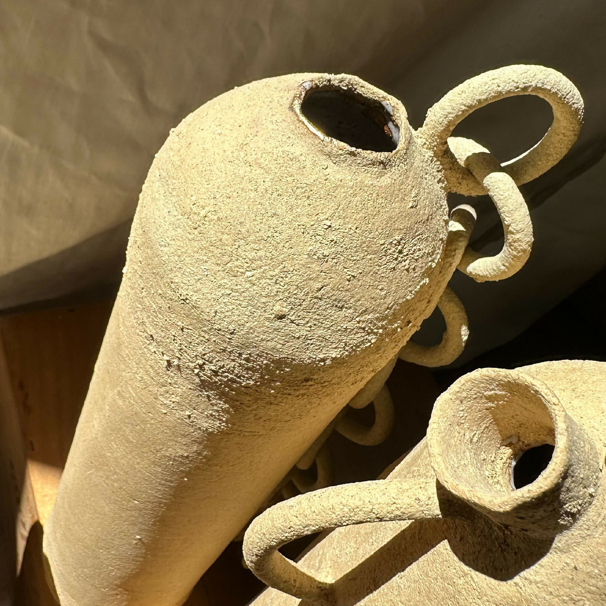 Vase en grès brut à texture granuleuse, anses en chaînons et ouvertures ovales