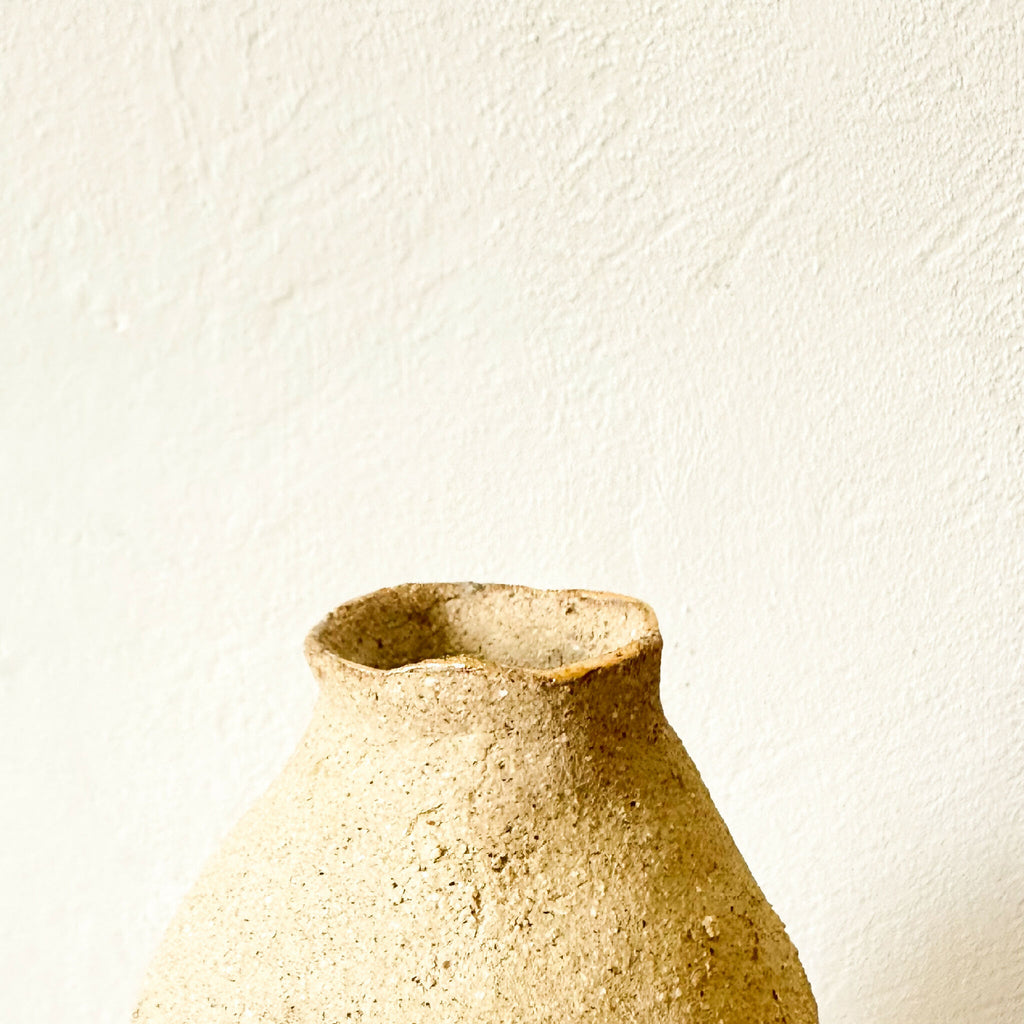 Petit vase en grès brut beige, ouverture évasée et bord irrégulier.