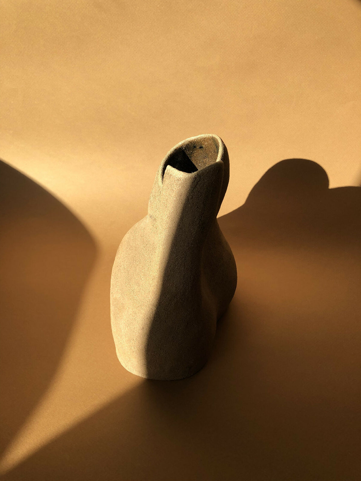 Vase beige en forme de goutte, ouverture fendue sombre sur le dessus