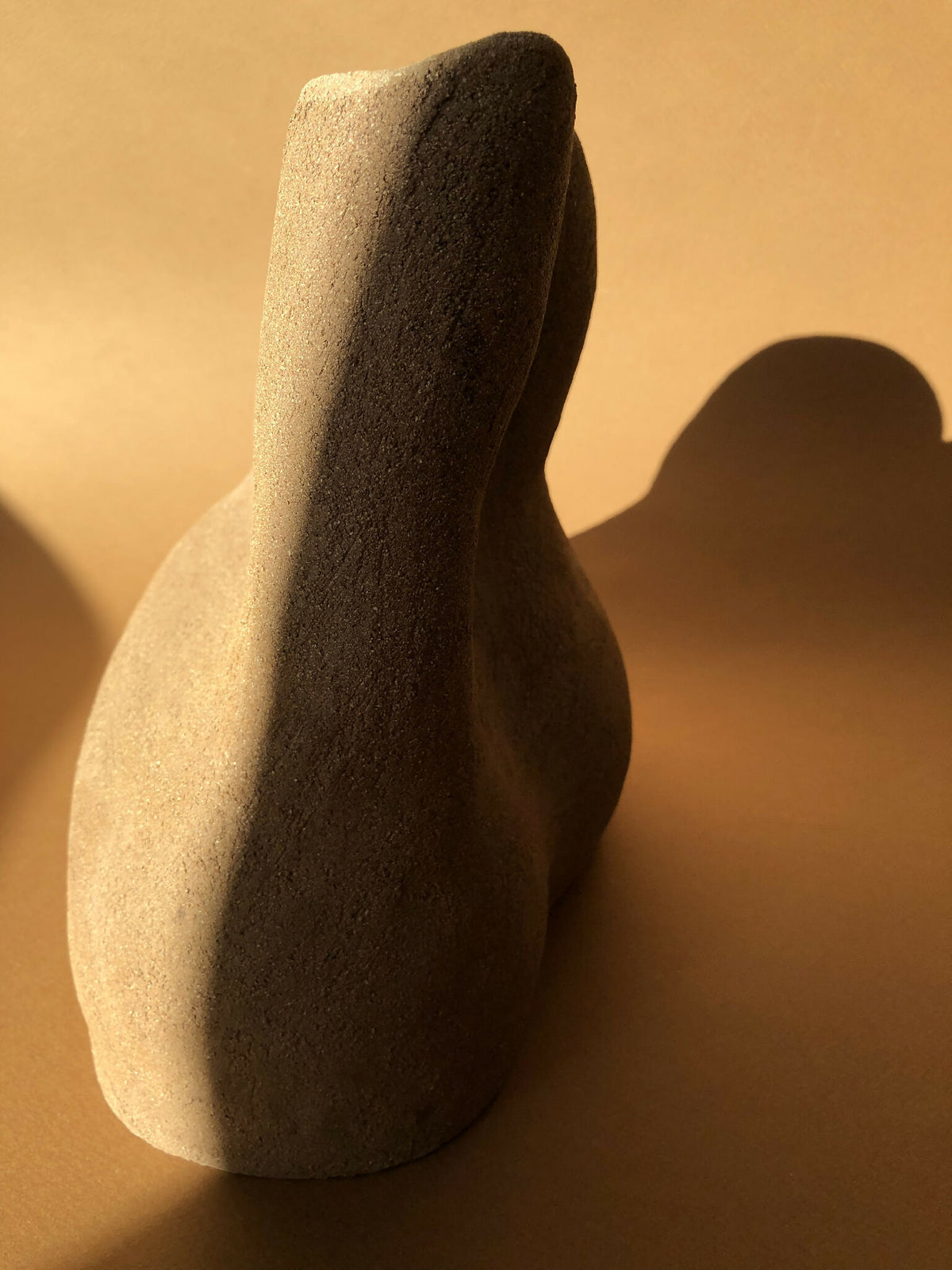Vase beige texturé, forme élancée évasée, petite ouverture sombre