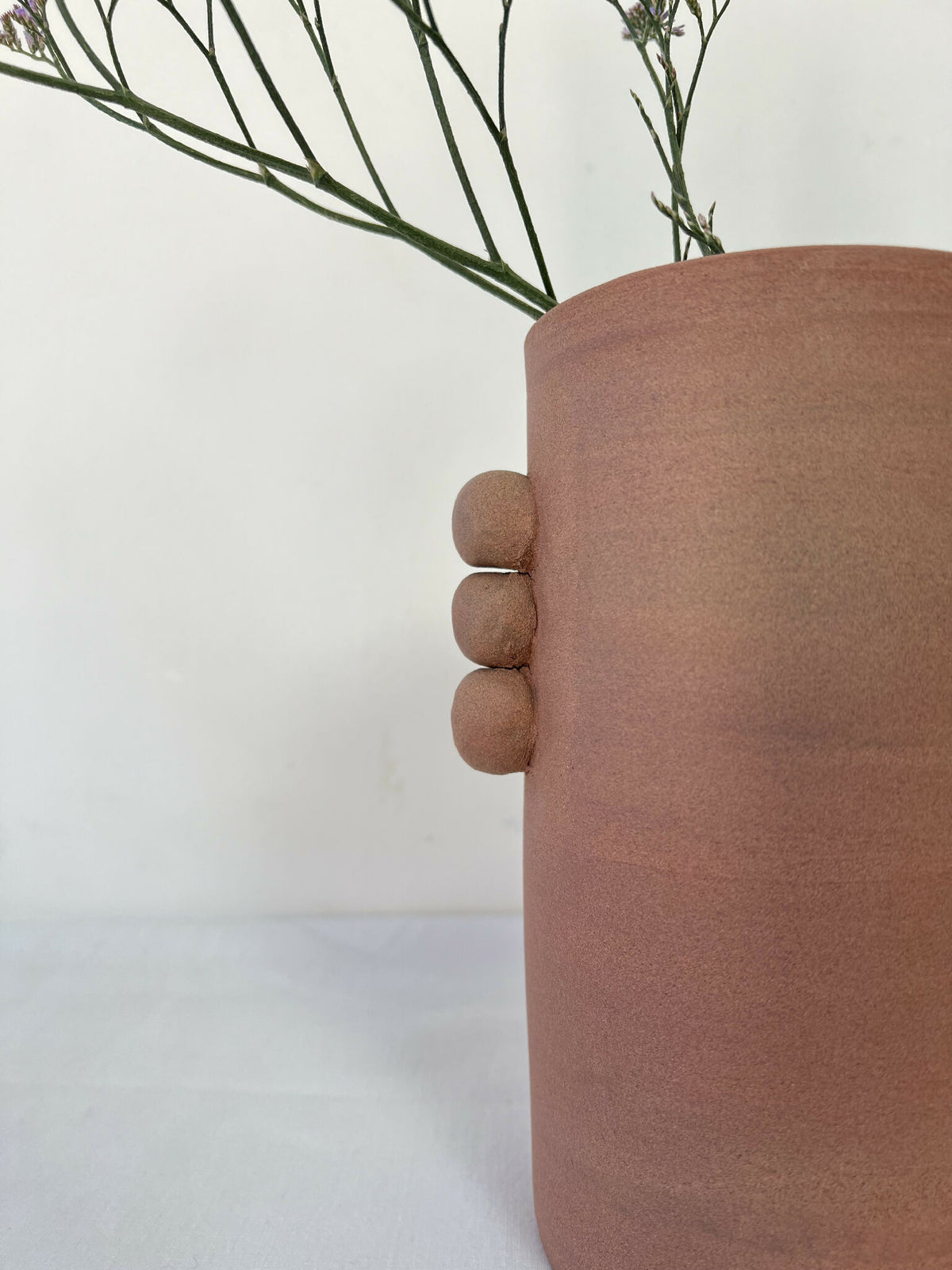 Vase en grès brun, gros plan sur la poignée en relief et la texture mate.