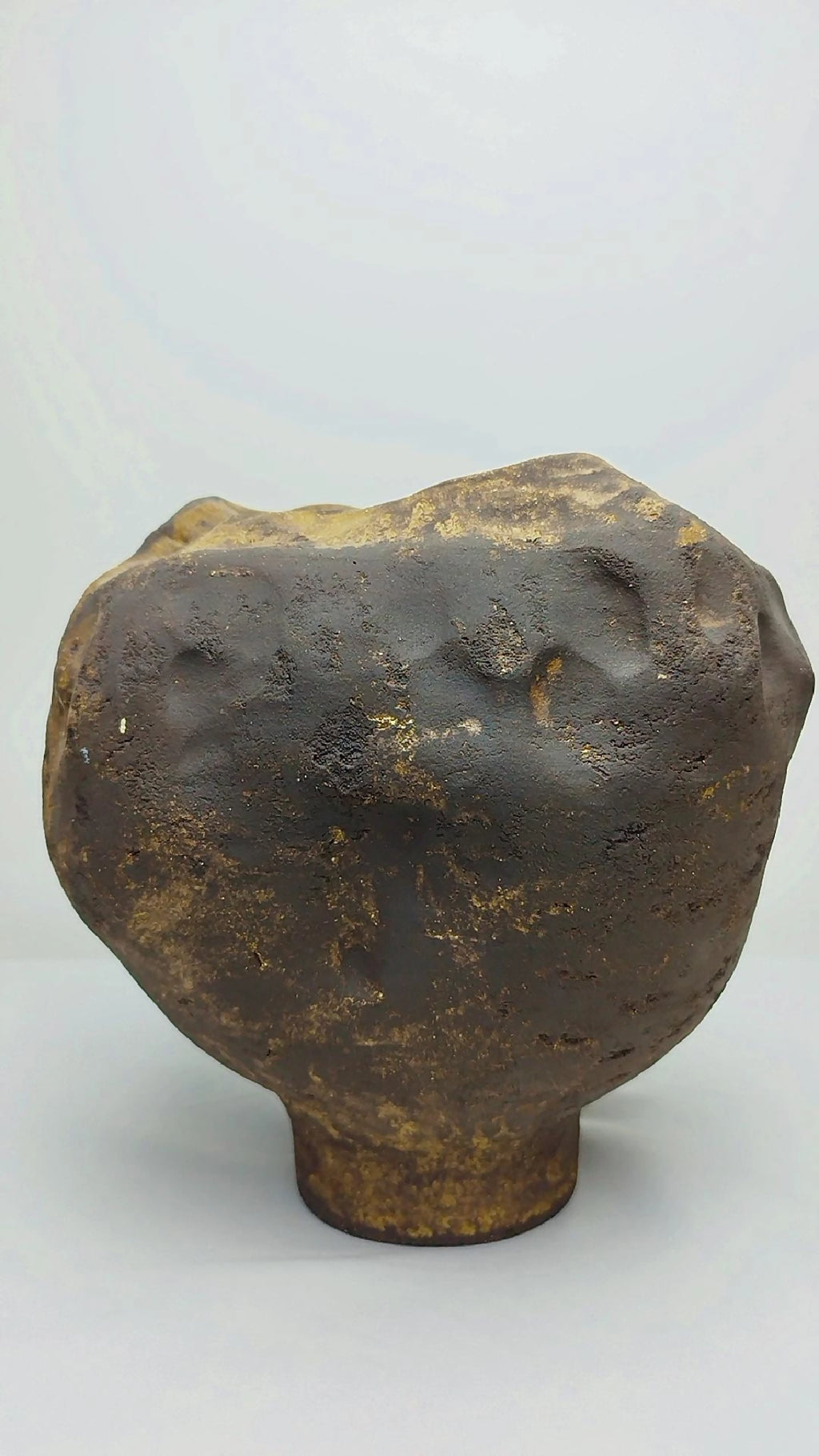 Vase sculptural en céramique noire et or, forme arrondie, ouverture en haut.
