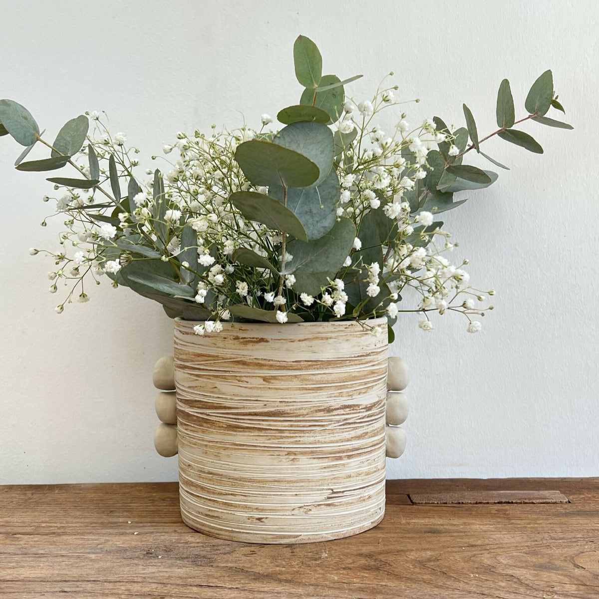 Vase en grès marbré beige cylindrique côtelé, renflements, bouquet de fleurs blanches.