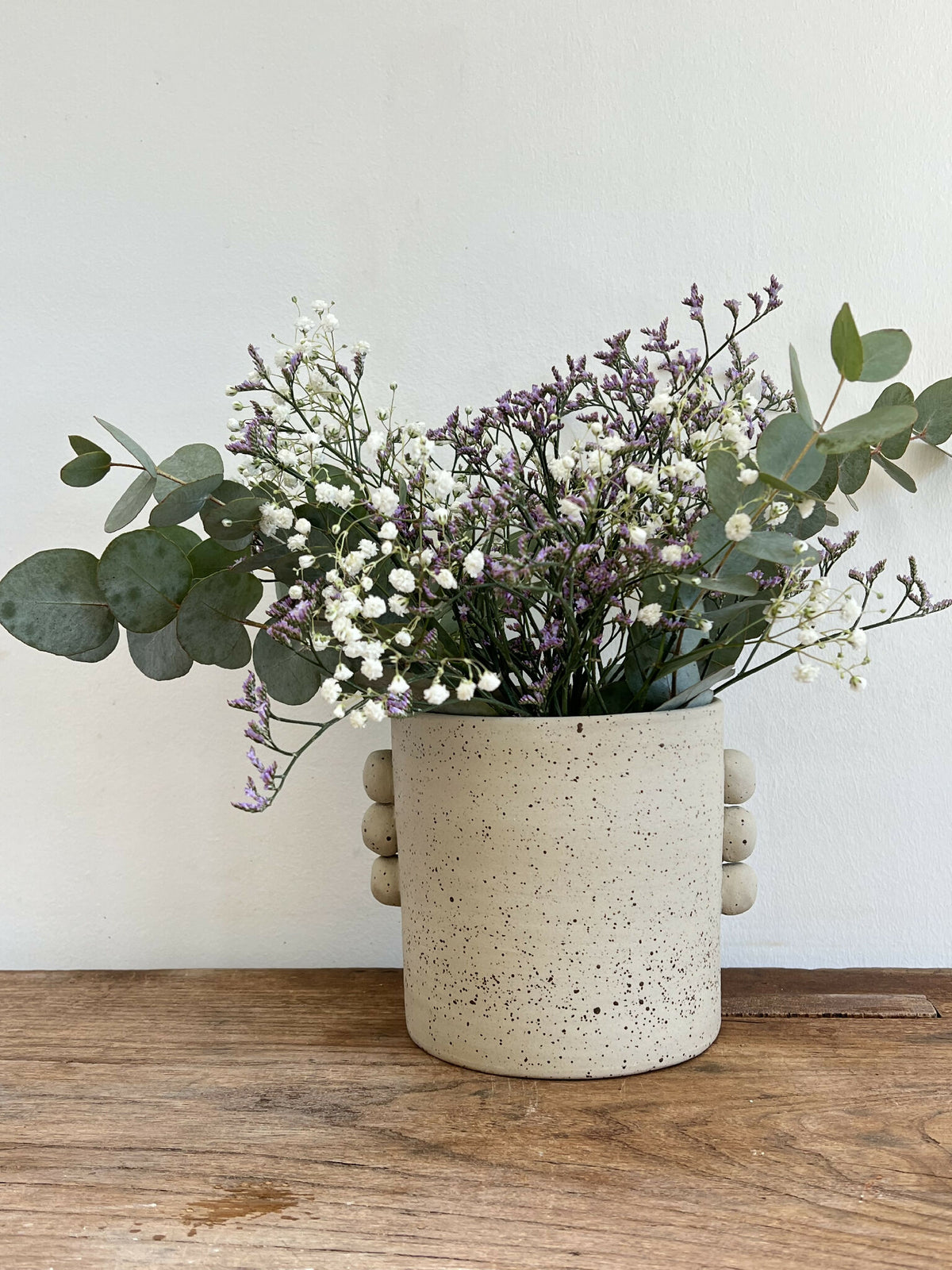 Vase en grès beige texturé, touches d’éclats, anses rondes, forme cylindrique.