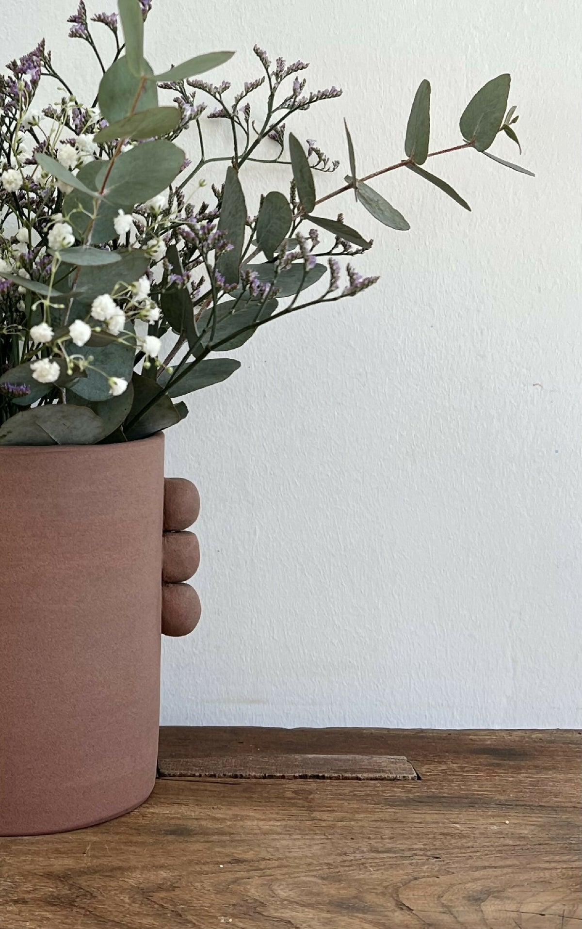 Vase en grès roux PALMA, vue latérale avec bouquet débordant de fleurs et feuillage.