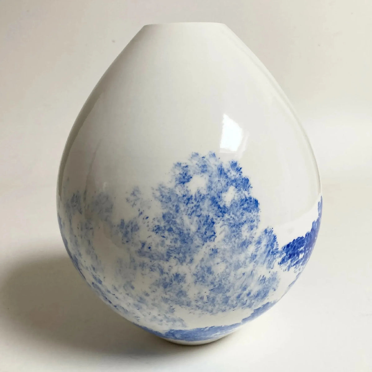 Vase en céramique goutte blanche avec paysage bleu, vue de côté.
