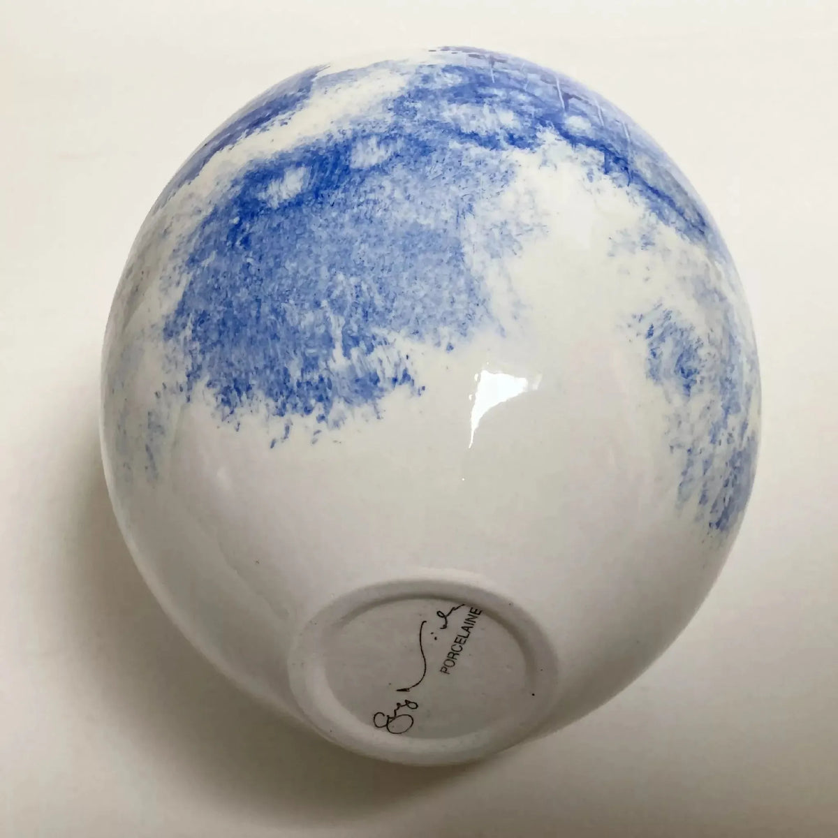Vase en céramique goutte blanche, base avec signature et motif bleu.