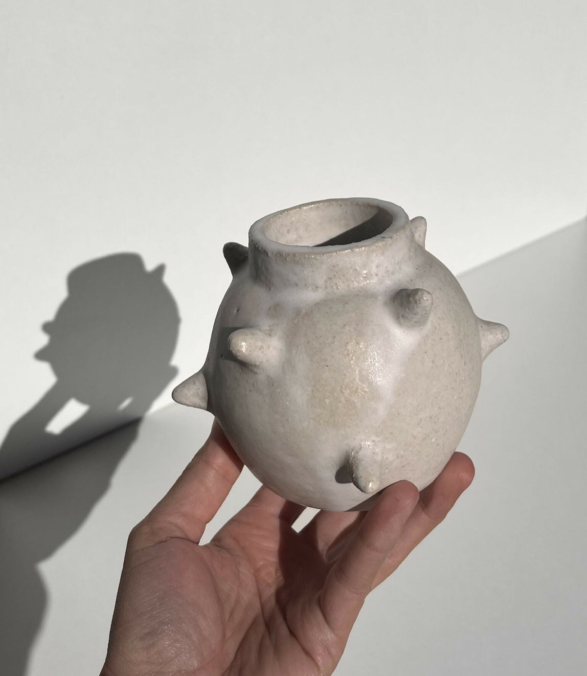 Vase en céramique gris argenté à reliefs, col évasé, tenue à la main
