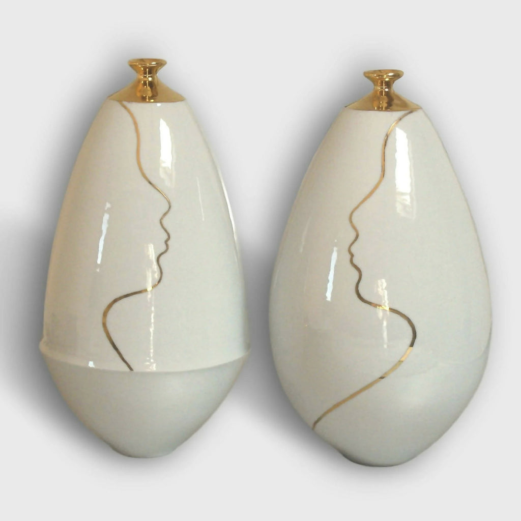 Vase soliflore en céramique blanche, col doré et contour de visage au trait.