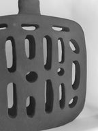 Vase noir ajouré : motifs d’ouvertures allongées sur la panse, vue rapprochée