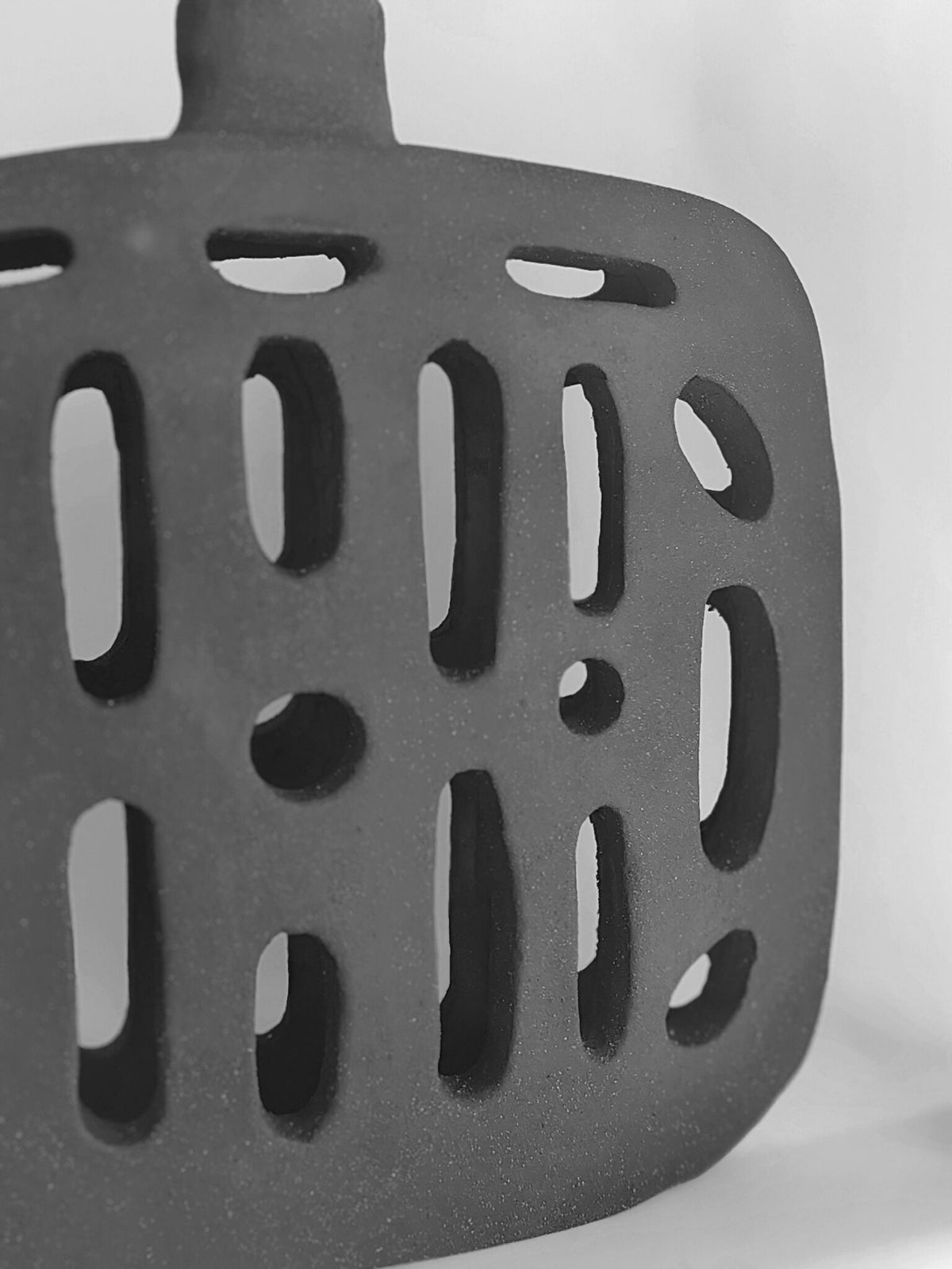 Vase noir ajouré : motifs d’ouvertures allongées sur la panse, vue rapprochée