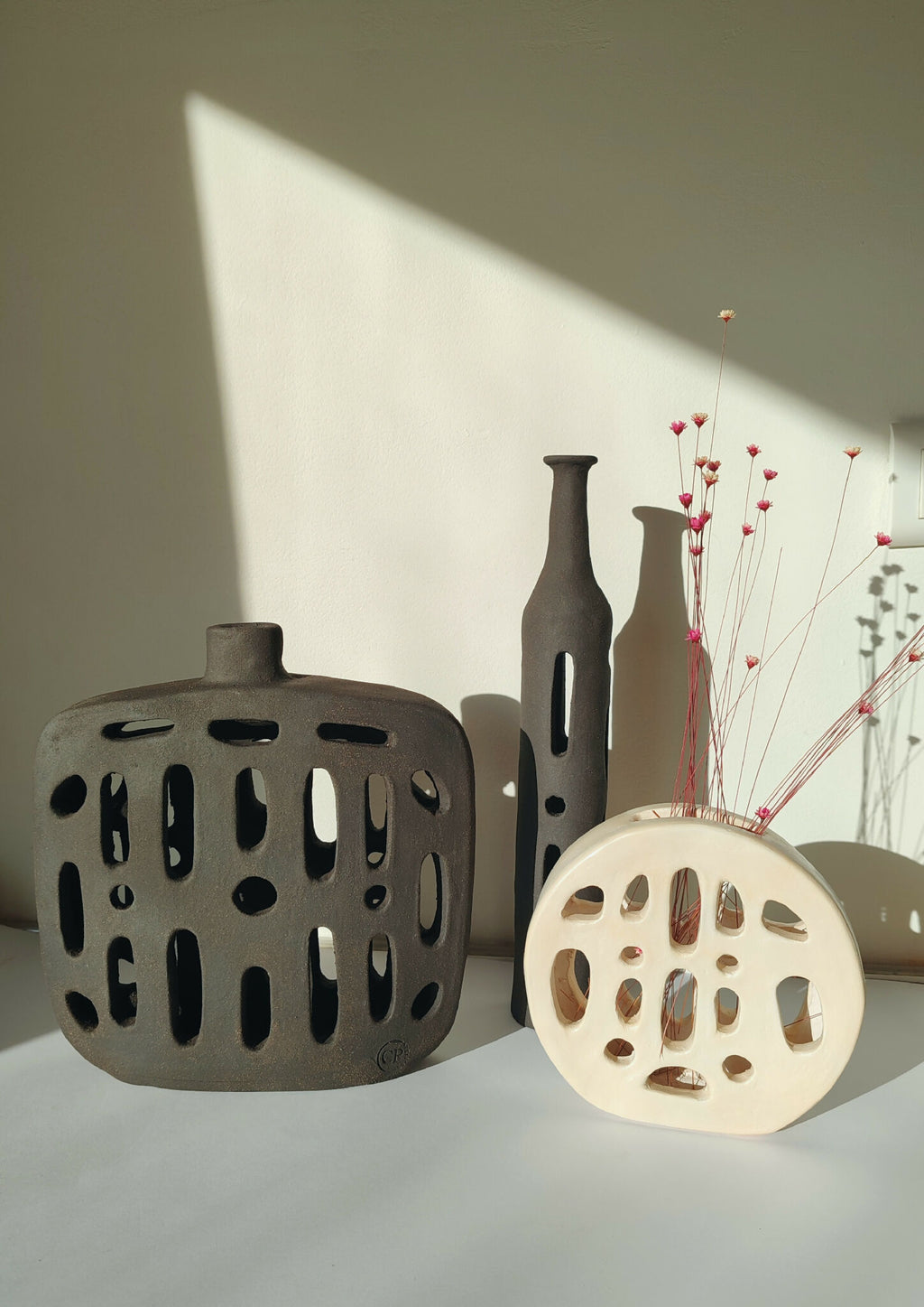 Vase noir ajouré avec ouverture, fleurs rouges et blanches dans les tiges