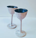 Deux verres à pied texturés, bords bleu foncé et coupes blanches sur tiges
