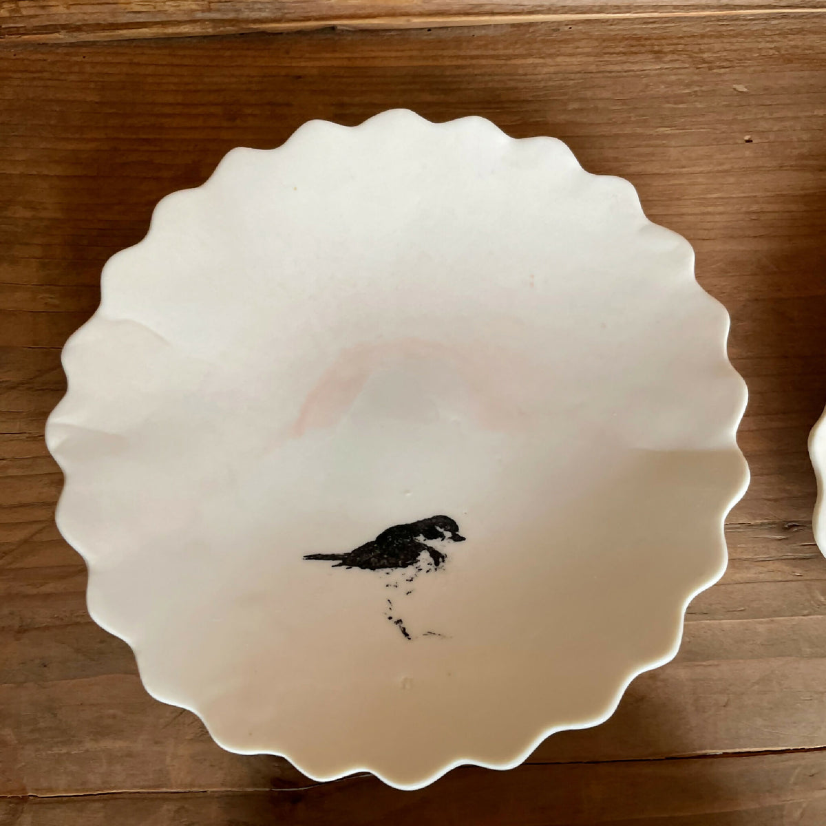 Coupelle en porcelaine blanche à bord festonné, oiseau sombre peint au centre